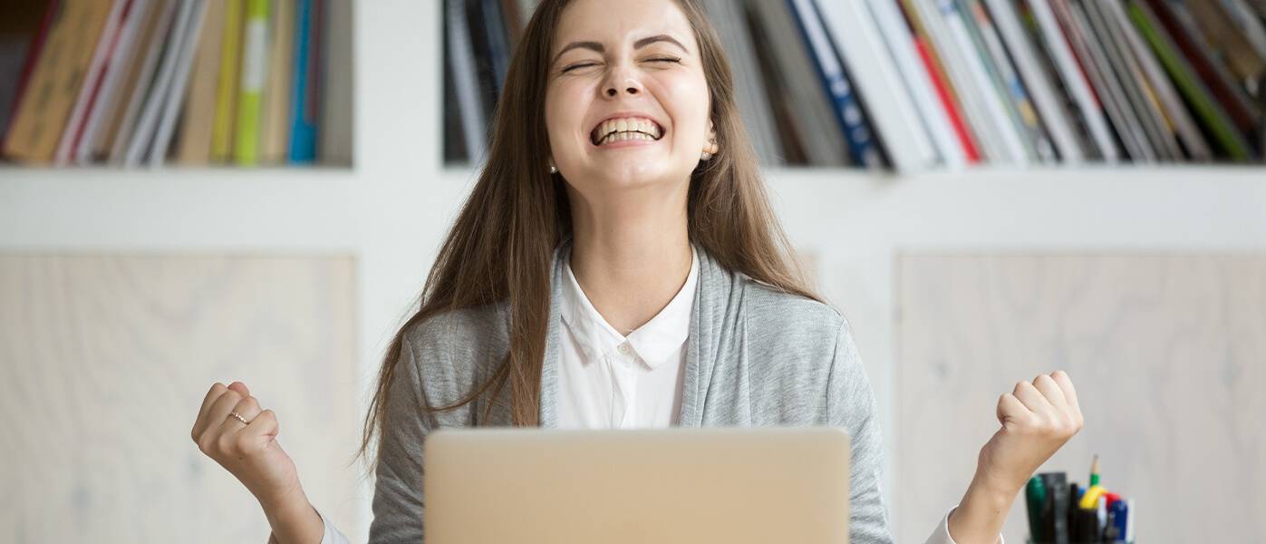 Extremely happy woman celebrating in front of computer screen